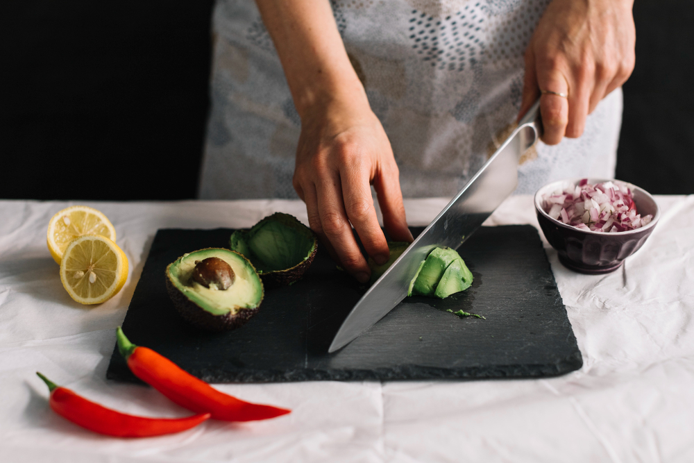 un femme coupant des légumes avec un couteau japonais